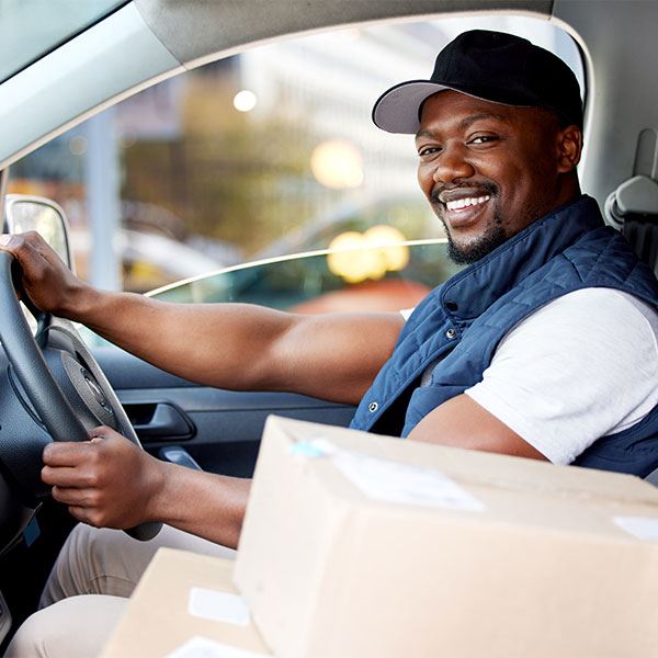 Delivery driver at the wheel of a van with parcels beside him