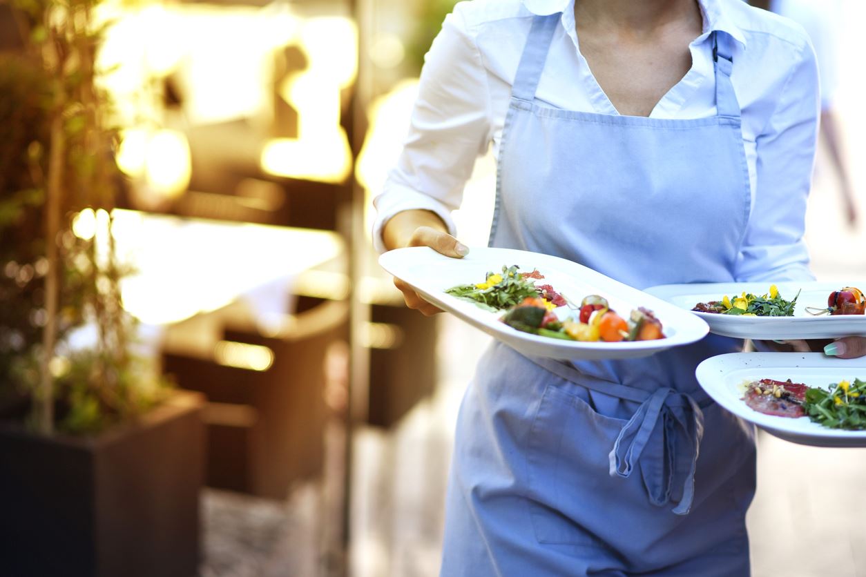 Restaurant server carrying plated meals to a table